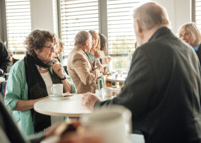 Eine Gruppe von Personen unterhält sich an Stehtischen.